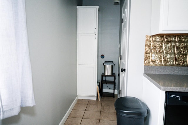 interior space with black dishwasher, baseboards, white cabinets, tile patterned floors, and backsplash