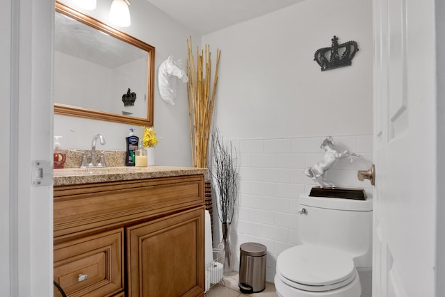 half bathroom featuring toilet, a wainscoted wall, vanity, and tile walls
