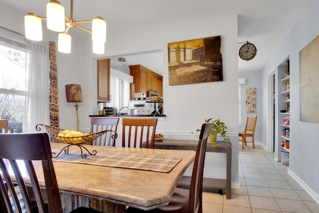 dining area featuring light tile patterned floors, baseboards, and a notable chandelier