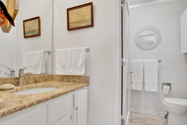 bathroom with toilet, baseboards, and vanity