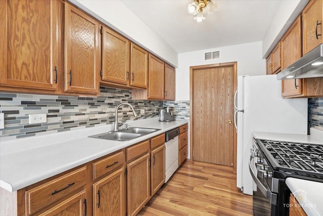 kitchen with dishwasher, light countertops, light wood-style floors, gas stove, and a sink