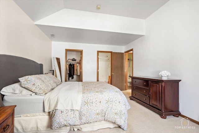 bedroom with a spacious closet, connected bathroom, lofted ceiling, light carpet, and a closet