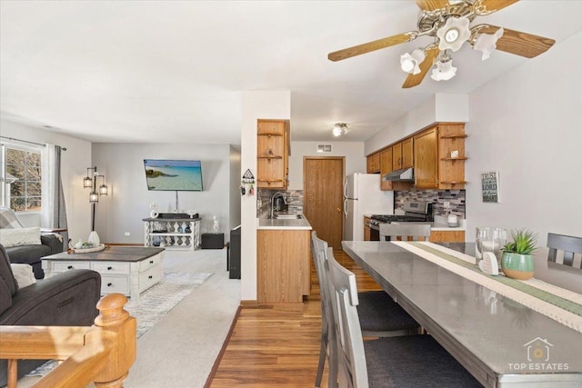 kitchen featuring tasteful backsplash, a sink, open floor plan, gas stove, and open shelves