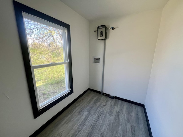 empty room with wood finished floors, baseboards, and plenty of natural light