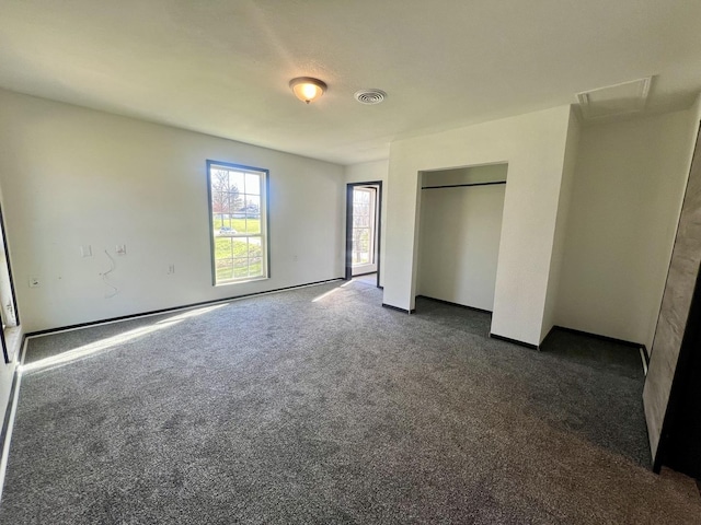unfurnished bedroom featuring dark carpet, a closet, baseboards, and visible vents