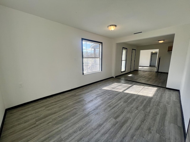 empty room with wood finished floors, baseboards, and visible vents