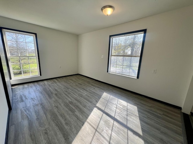 unfurnished room featuring plenty of natural light, baseboards, and wood finished floors
