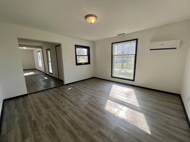 interior space with visible vents, baseboards, wood finished floors, and a wall mounted air conditioner