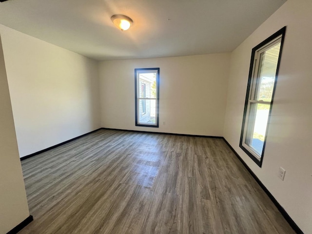 empty room featuring baseboards, wood finished floors, and a healthy amount of sunlight