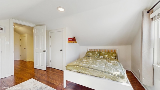 bedroom featuring lofted ceiling, wood finished floors, and baseboards