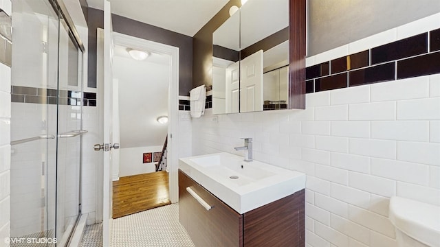 bathroom with tasteful backsplash, tile walls, a shower stall, and vanity