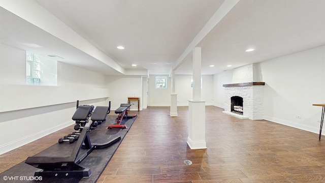 exercise room featuring a stone fireplace, recessed lighting, baseboards, and wood finished floors