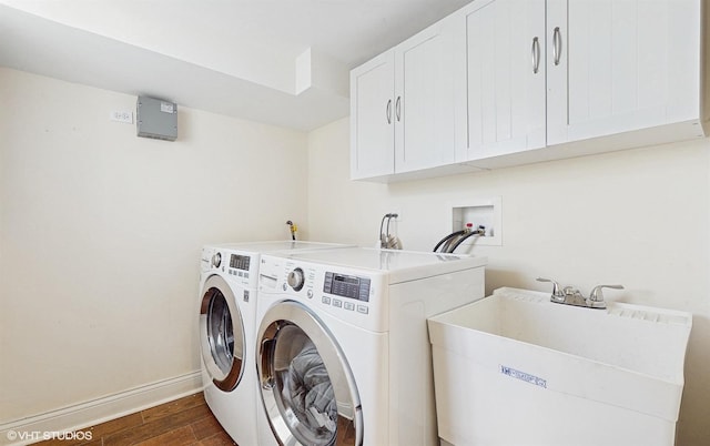 clothes washing area with dark wood-type flooring, a sink, cabinet space, baseboards, and washing machine and clothes dryer