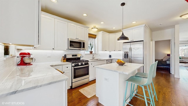 kitchen featuring a sink, stainless steel appliances, decorative backsplash, and dark wood-style flooring