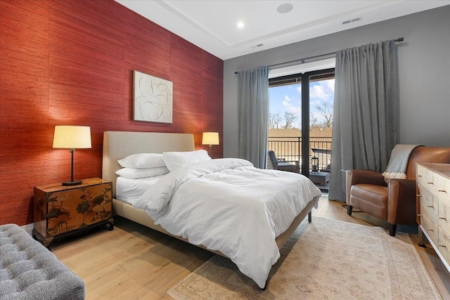 bedroom featuring an accent wall, visible vents, access to outside, light wood-type flooring, and wallpapered walls