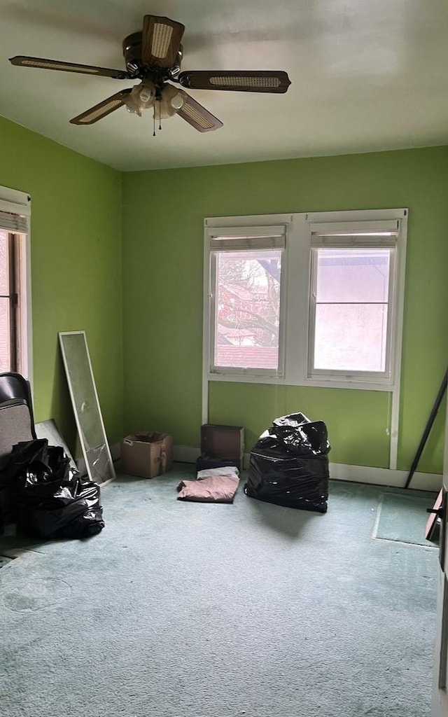 interior space with a ceiling fan, carpet flooring, and baseboards