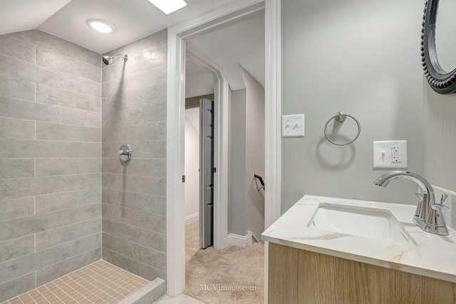 bathroom with tiled shower, vaulted ceiling, and vanity