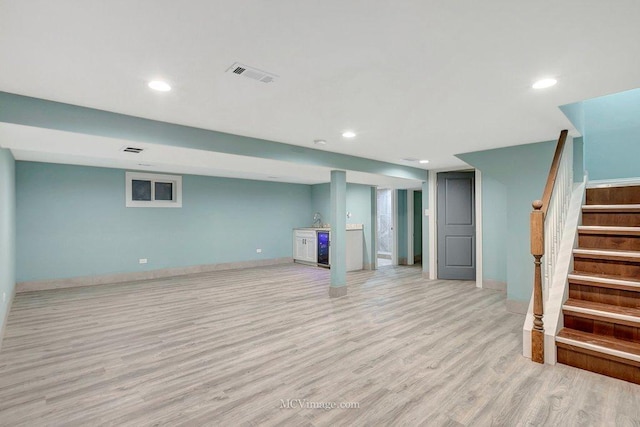 finished basement with recessed lighting, visible vents, light wood-type flooring, baseboards, and stairs