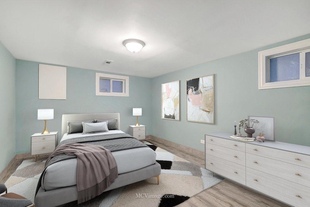 bedroom with light wood-style flooring, visible vents, and baseboards