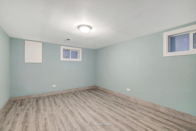 finished basement featuring baseboards, visible vents, and wood finished floors