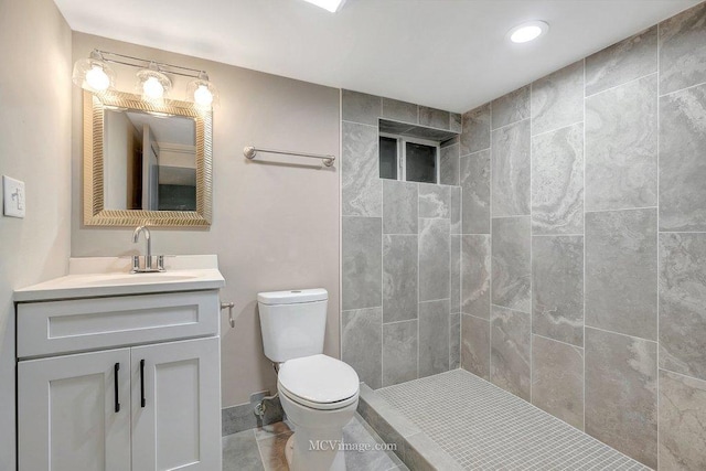 full bath with tile patterned flooring, a tile shower, vanity, and toilet