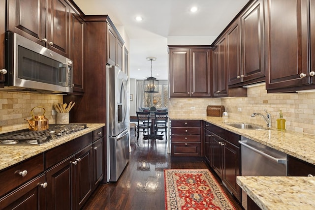 kitchen featuring light stone countertops, a sink, stainless steel appliances, dark wood-type flooring, and tasteful backsplash