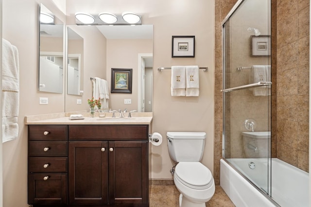 full bath featuring vanity, tile patterned floors, toilet, and combined bath / shower with glass door