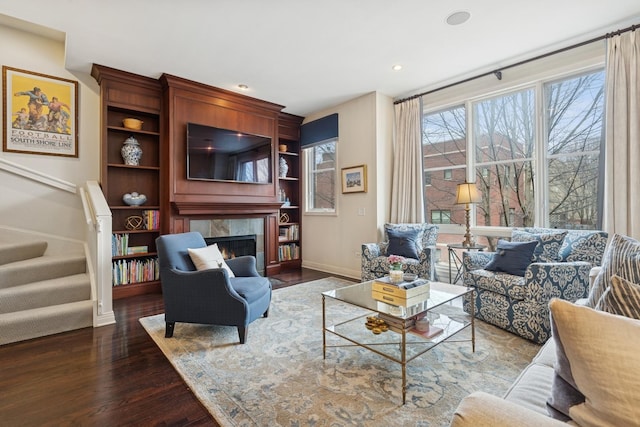 living room with a wealth of natural light, stairway, dark wood-style floors, and a tile fireplace