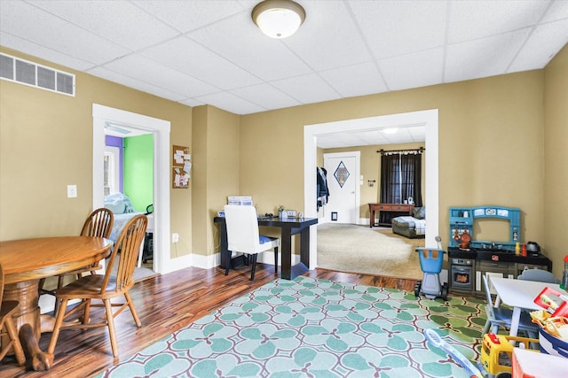 office area featuring a paneled ceiling, wood finished floors, visible vents, and baseboards