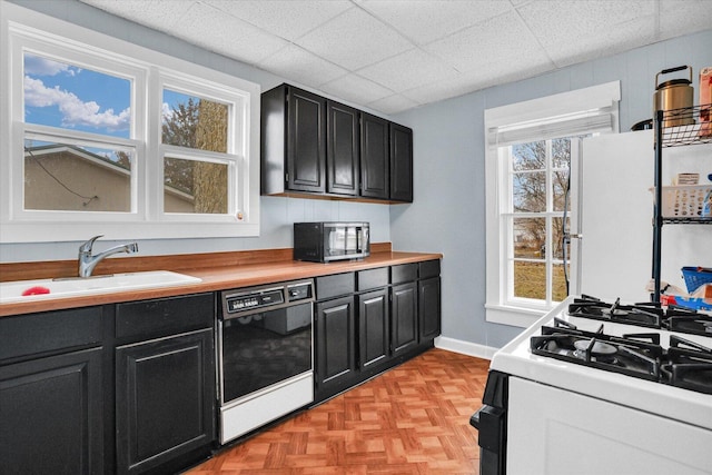 kitchen featuring a sink, dark cabinets, gas range oven, and dishwasher