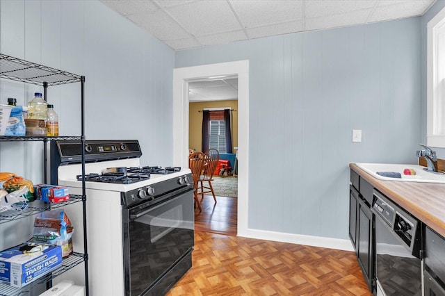 kitchen with a drop ceiling, a sink, light countertops, dishwasher, and range with gas cooktop