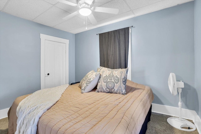 bedroom featuring a paneled ceiling, carpet, baseboards, and ceiling fan