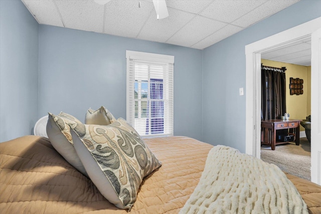 carpeted bedroom with a drop ceiling and a ceiling fan