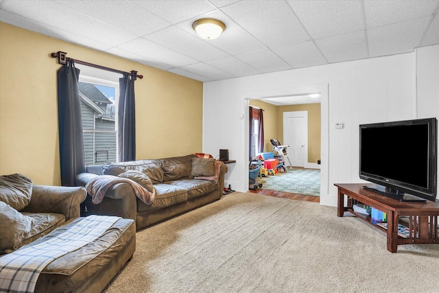 living room featuring a paneled ceiling and carpet