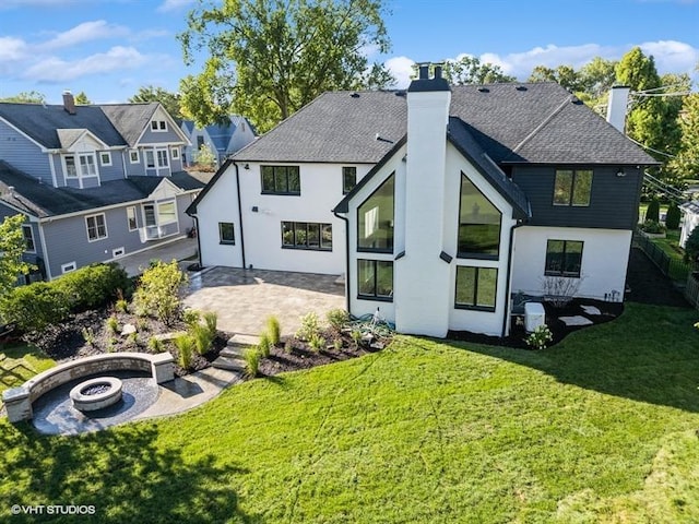 rear view of property featuring an outdoor fire pit, a shingled roof, a patio, a chimney, and a yard