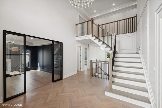 stairway with a towering ceiling, baseboards, a chandelier, and recessed lighting