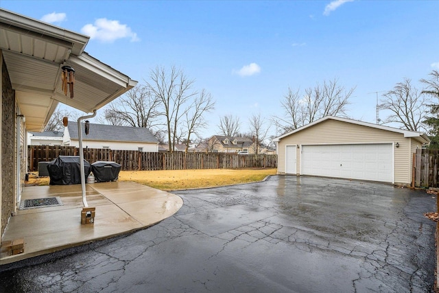 view of patio / terrace with an outbuilding, a detached garage, and fence