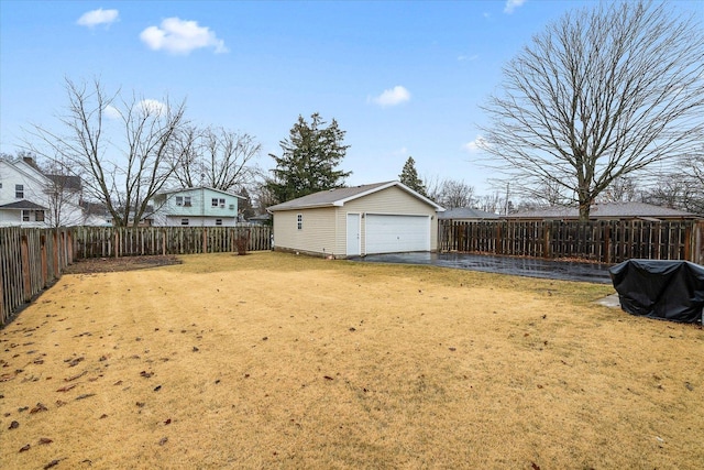 view of yard featuring an outbuilding, a fenced backyard, and a detached garage