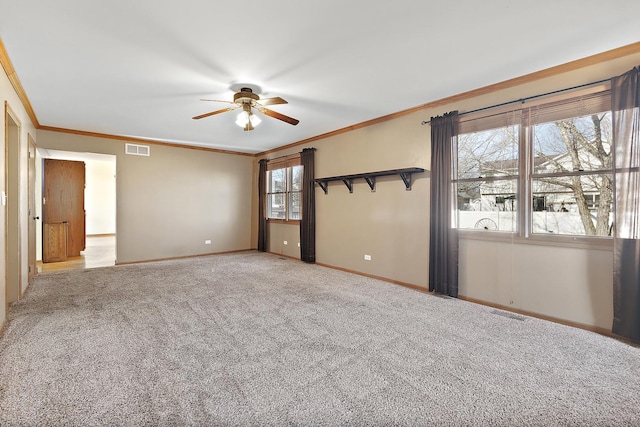 carpeted spare room featuring baseboards, a ceiling fan, visible vents, and ornamental molding