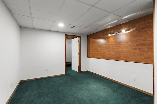 spare room featuring visible vents, baseboards, dark colored carpet, and a drop ceiling