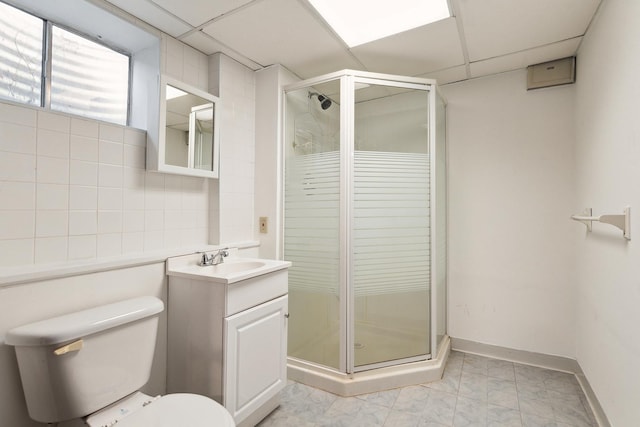 full bath featuring vanity, baseboards, a stall shower, a drop ceiling, and toilet