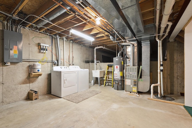 unfinished below grade area featuring heating unit, washing machine and clothes dryer, electric panel, water heater, and a sink