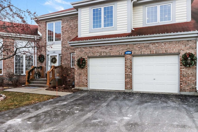 view of front of house with driveway, brick siding, and an attached garage