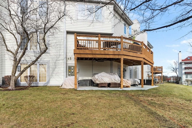 rear view of property featuring a patio area, a lawn, and a wooden deck