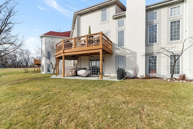 rear view of property featuring a yard, a chimney, a wooden deck, and a patio