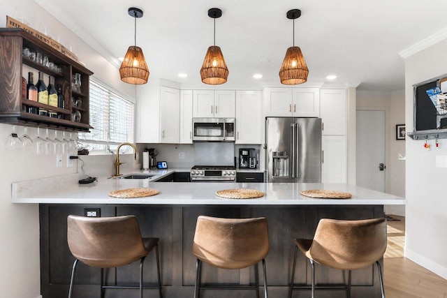 kitchen featuring stainless steel appliances, a peninsula, a sink, light countertops, and ornamental molding