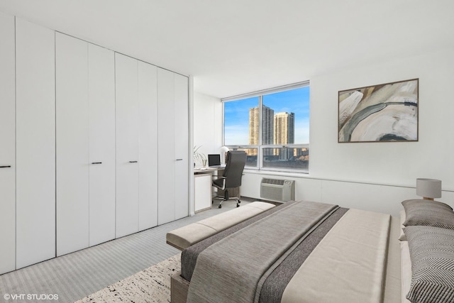 bedroom with a view of city, a closet, a wall unit AC, and carpet flooring