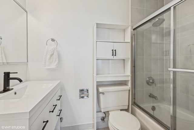 bathroom featuring toilet, shower / bath combination with glass door, and vanity