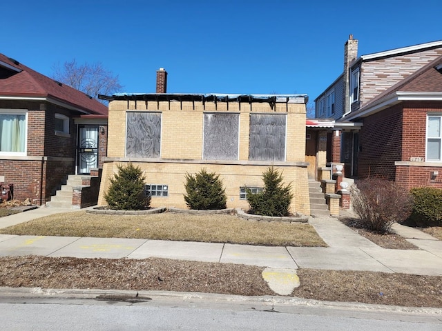 view of front of home with brick siding and a chimney