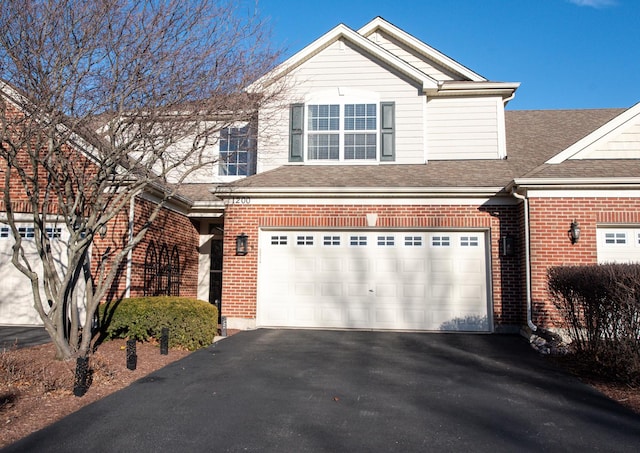 view of front of property with a garage, aphalt driveway, roof with shingles, and brick siding